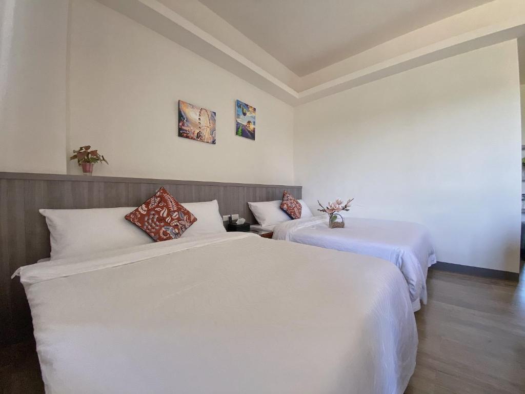 馬公市にある鎖港山水文旅民宿の白い壁とウッドフロアの客室で、ベッド2台が備わります。