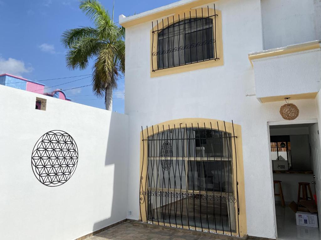 a white building with a gate and a palm tree at flower of life in Cancún