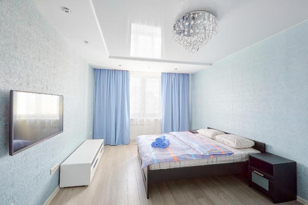um pequeno quarto com uma cama e um lustre em Apartments Abajur on Pichugina street 6 em Kurgan