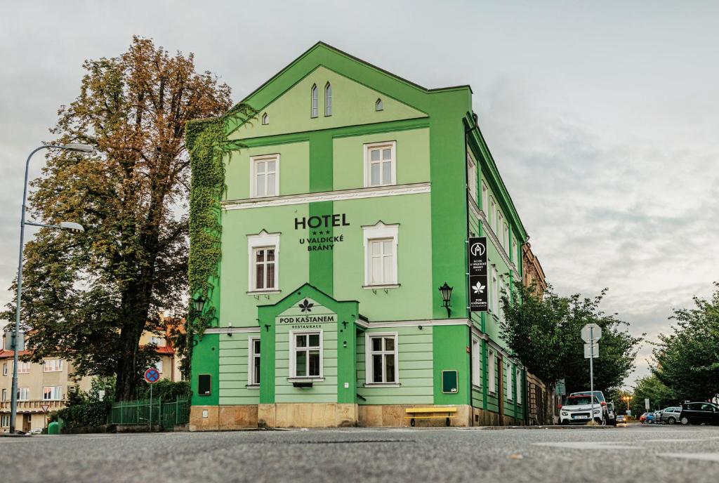 un edificio verde y blanco en la esquina de una calle en Hotel U Valdické brány en Jičín