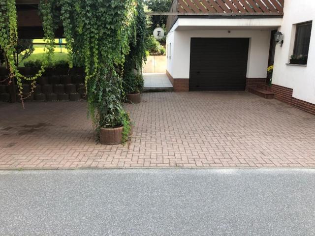 ein Haus mit einer Garage mit einer Ziegelsteinfahrt in der Unterkunft Ferienhaus Morgensonne in Neustadt in Sachsen