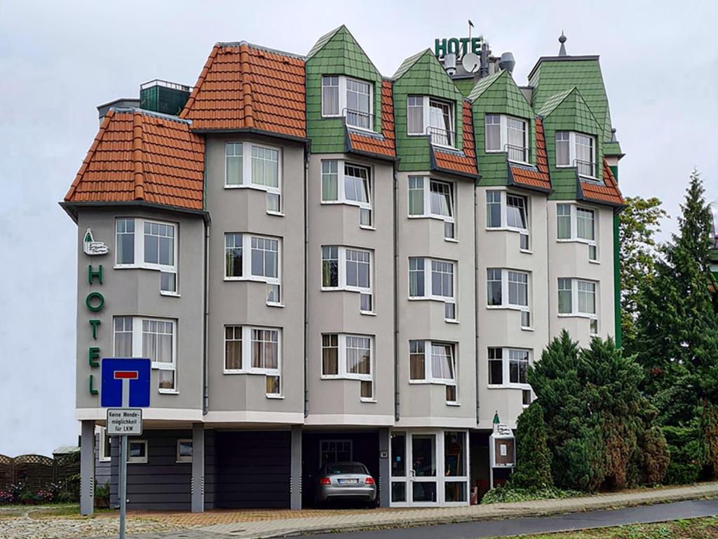 un gran edificio con techo de baldosa en una calle en Zum Grünen Turm, en Hohen Neuendorf