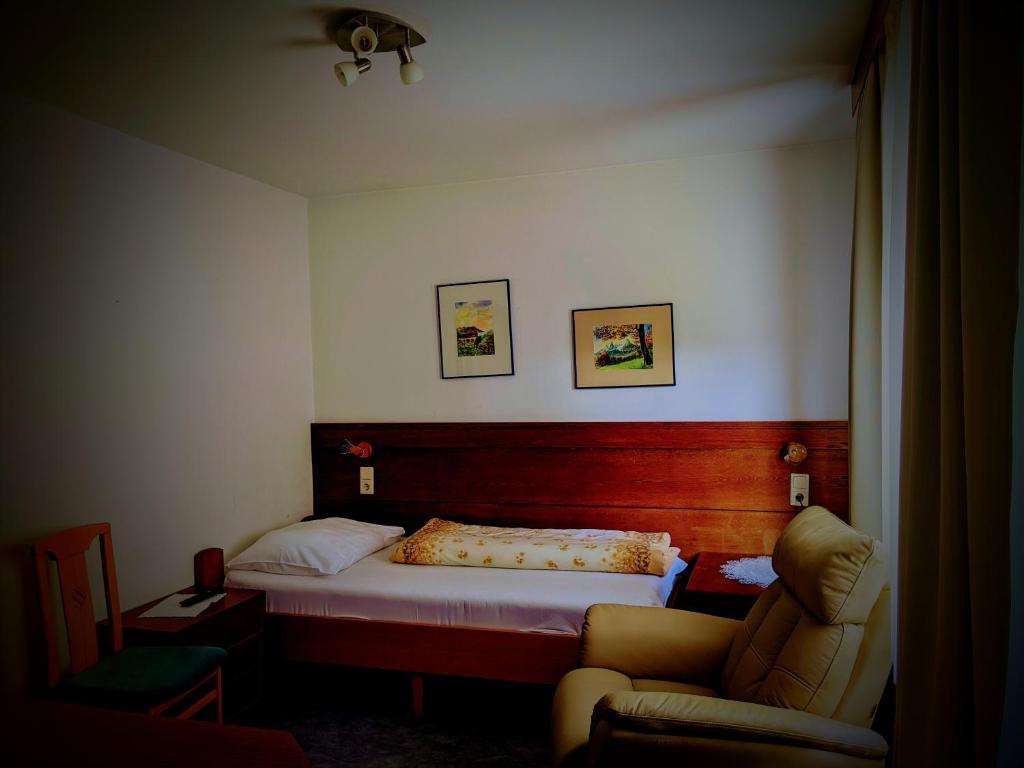 a small bedroom with a bed and a chair at Pension Alpina in Obsteig