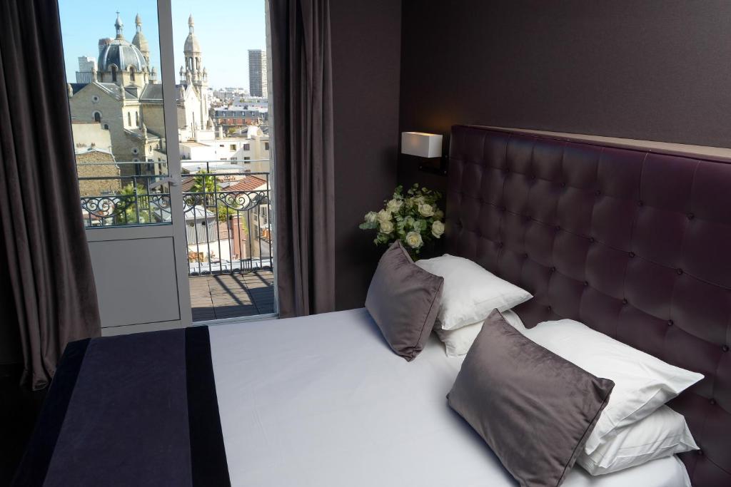 una camera da letto con un grande letto con una grande finestra di Hôtel Saint-Charles a Parigi