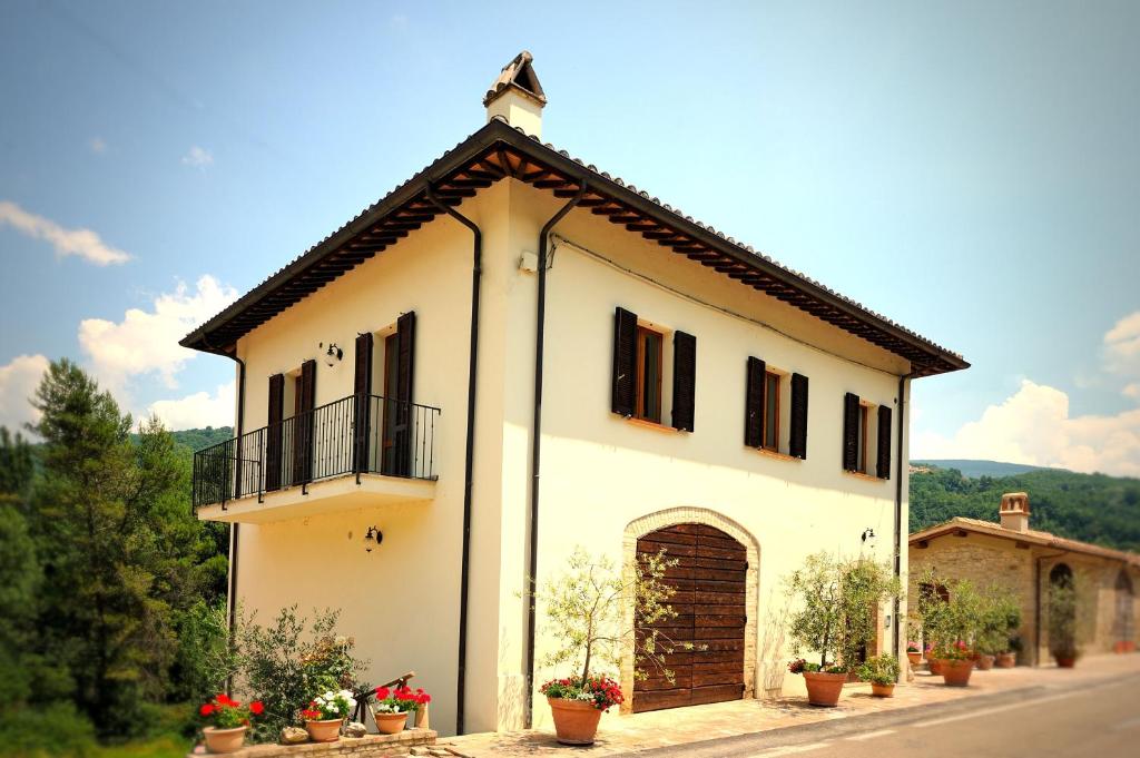 Casa blanca grande con balcón y plantas en Agriturismo Casa Brunori, en Foligno