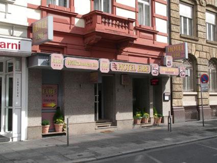 a red building on a street with signs on it at Hotel Elbe Street 34 in Frankfurt