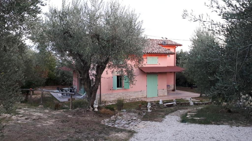 une maison rose avec un arbre devant elle dans l'établissement Le Rondini, à Montecosaro