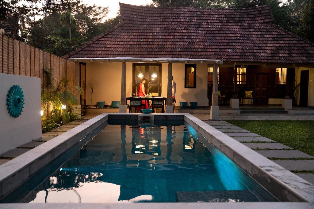 a house with a swimming pool in front of a house at Marari Villas - Private Pool Villas in Mararikulam