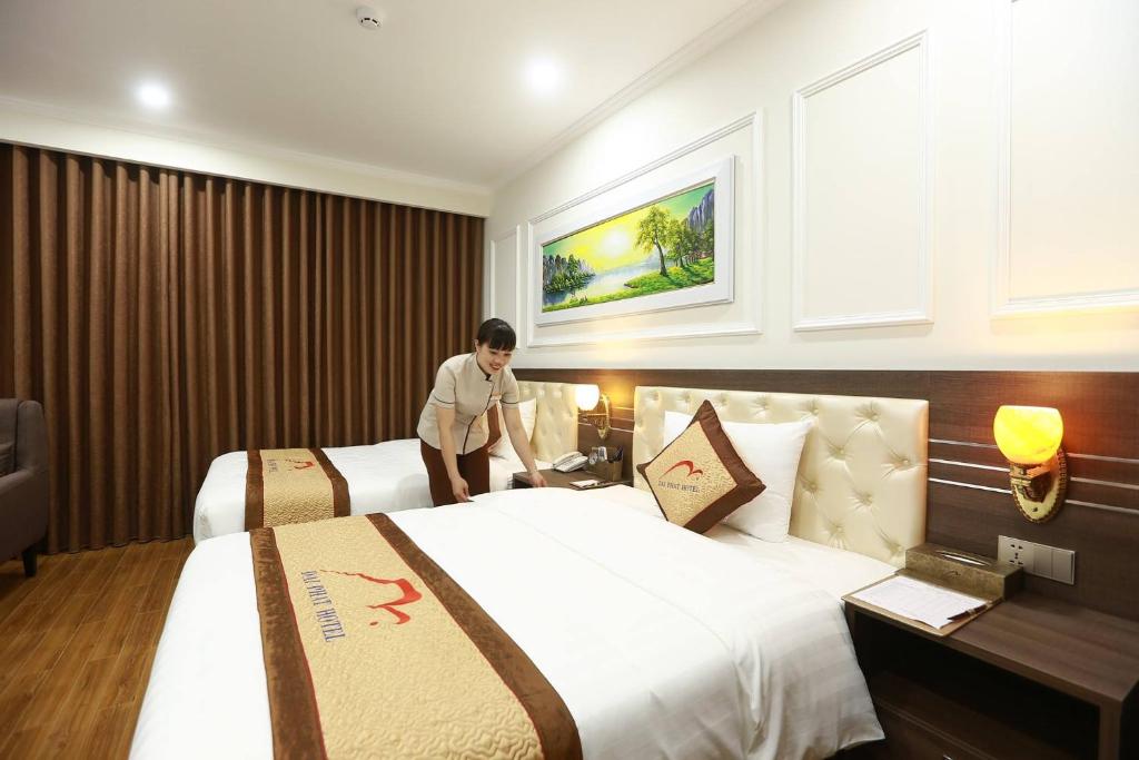a man standing between two beds in a hotel room at Dai Phat Luxury Hotel & Apartment in Hanoi