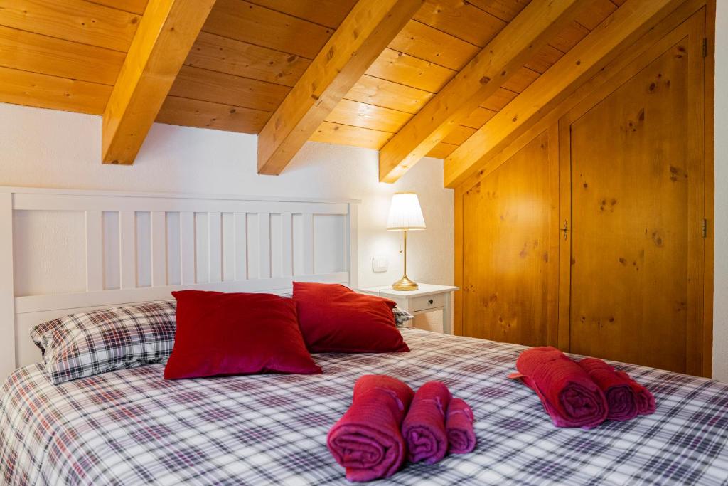 a bed with red pillows and red towels on it at Mansarda Villa Adele in Santo Stefano dʼAveto