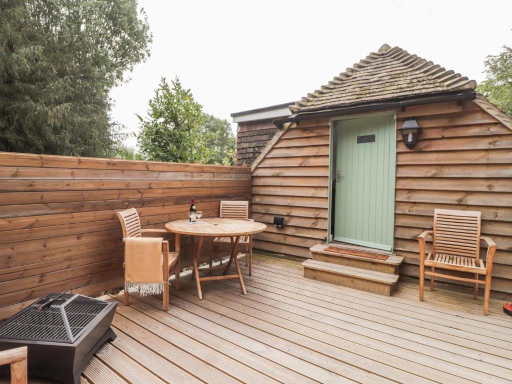 un patio con mesa y sillas en una terraza de madera en Ella's Loft en Canterbury