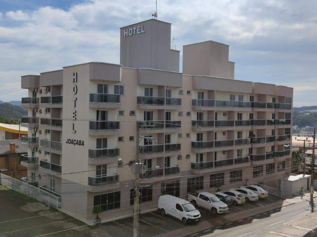 a hotel with cars parked in a parking lot at Hotel Joaçaba in Joaçaba