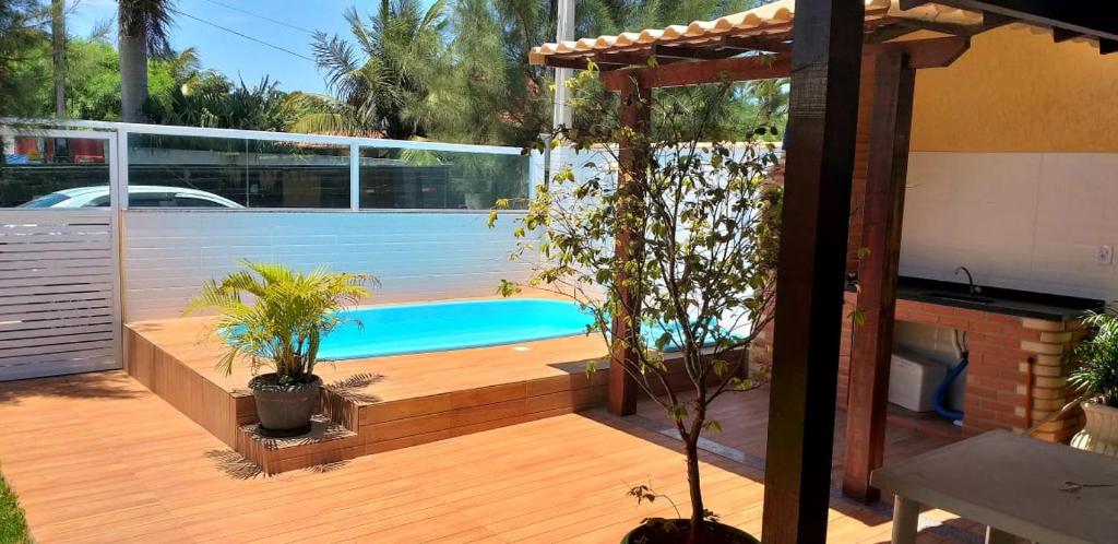 a backyard with a swimming pool and a wooden deck at CASA DE PRAIA - Verão Vermelho I - Cabo Frio - Unamar in Cabo Frio