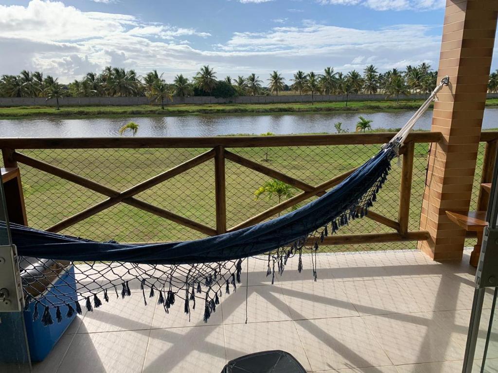 uma rede de descanso num alpendre com vista para um lago em Condomínio e resort Villa das Águas - Praia do Saco SE em Estância