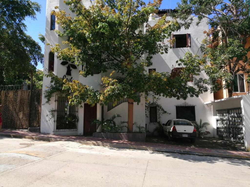 a white building with a car parked in front of it at Ceiba Studios in Zihuatanejo