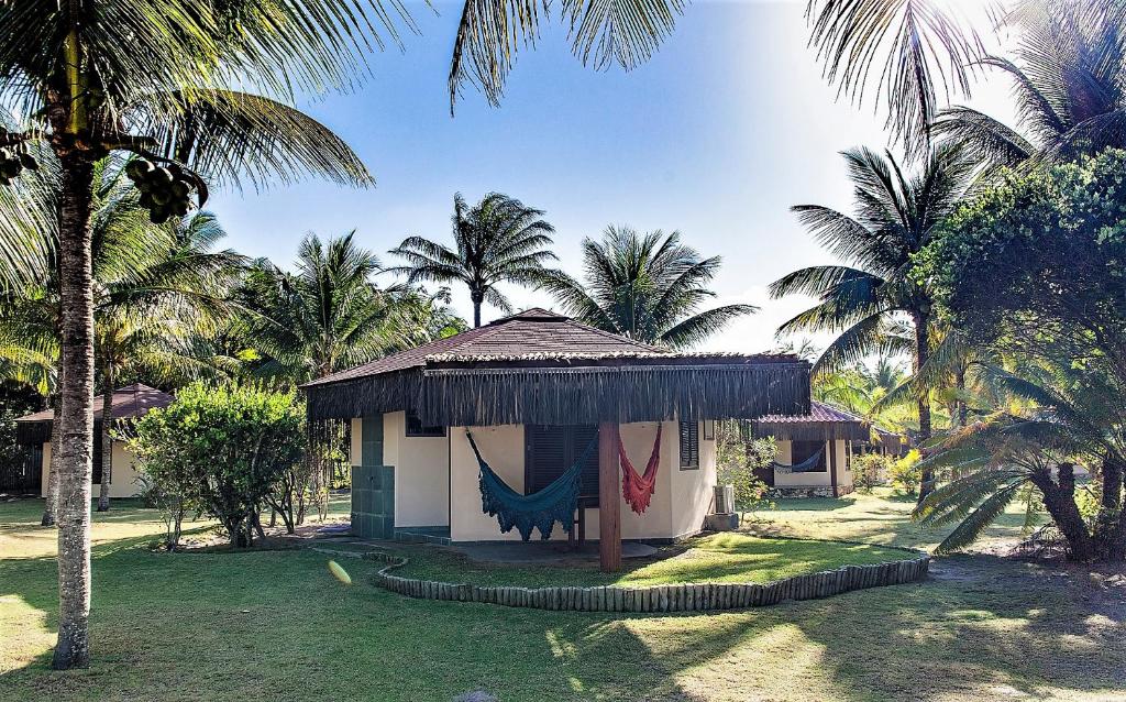 a small hut with a hammock in a yard with palm trees at Pousada Lagoa do Cassange in Marau