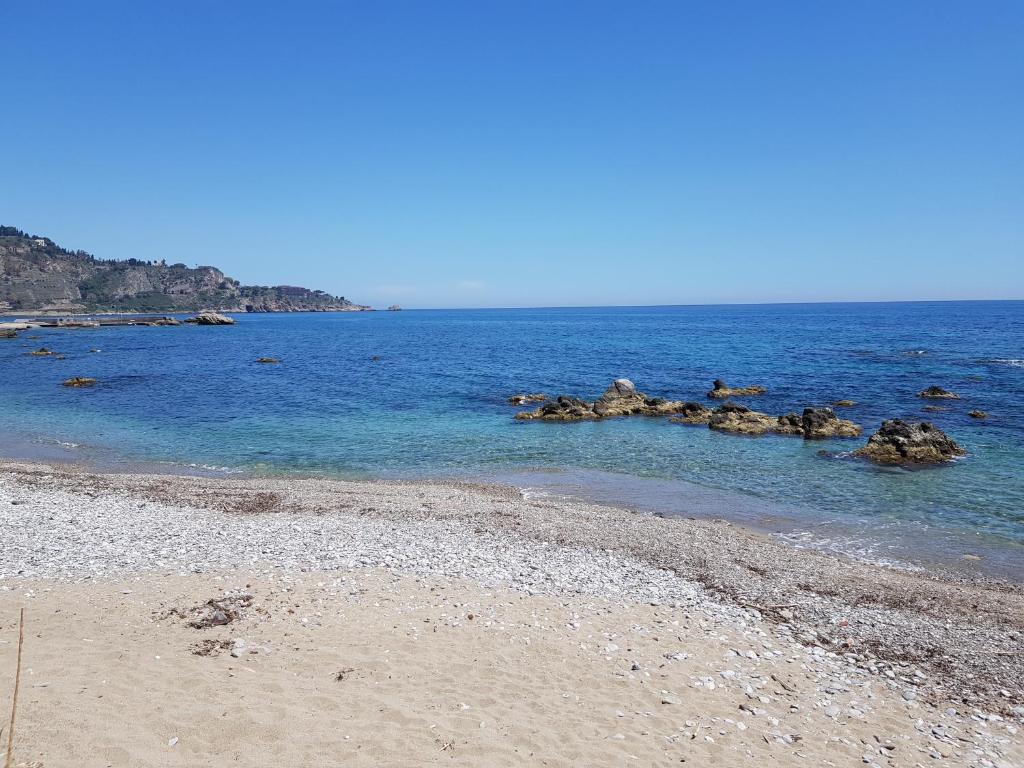 una spiaggia con alcune rocce in acqua di Appartamenti via Lombardo a Giardini Naxos