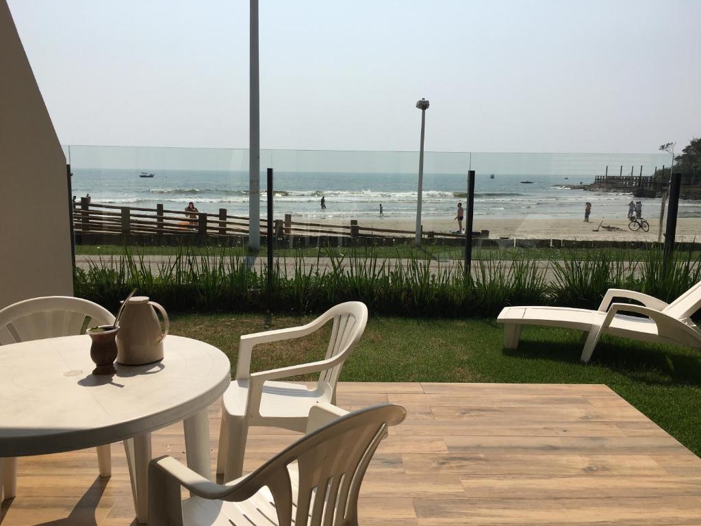 Un patio con mesa y sillas y la playa. en Férias a beira mar - Brilhos do sol, en Bombinhas