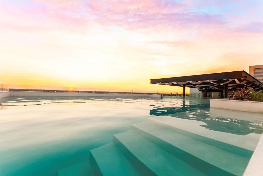 uma piscina com um pôr-do-sol ao fundo em NH Collection Merida Paseo Montejo em Mérida