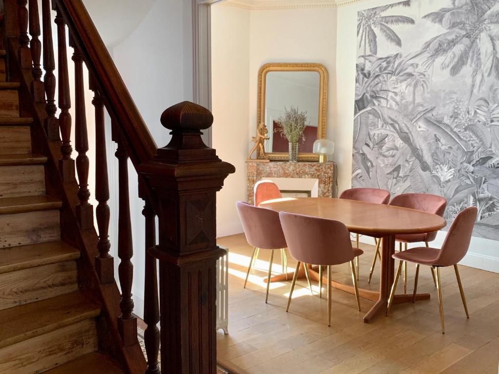 a dining room with a wooden table and pink chairs at La Villégiature et la Maisonnette in Vichy