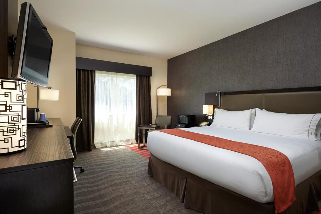 a hotel room with a large bed and a flat screen tv at Holiday Inn Express & Suites Naples Downtown - 5th Avenue by IHG in Naples