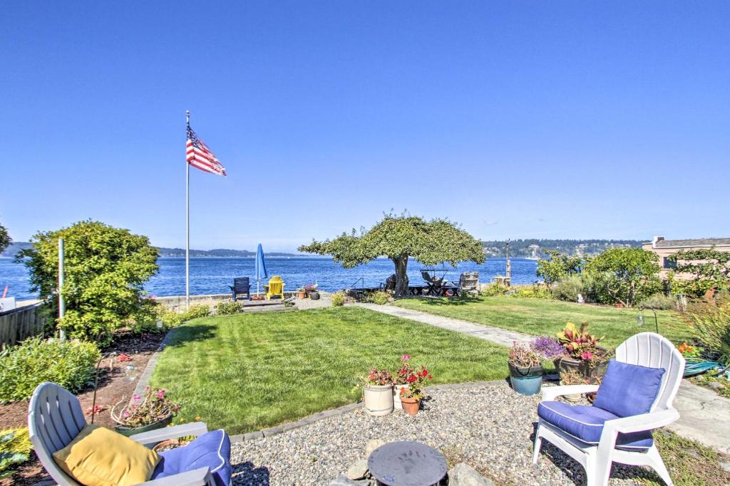 a patio with two chairs and an american flag at Ideally Located Waterfront Home - Puget Sound View in University Place