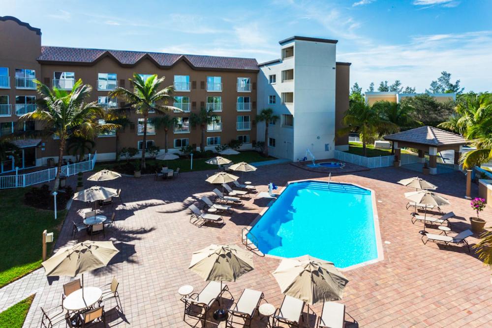an outdoor pool with umbrellas and chairs and a hotel at Holiday Inn Express & Suites Naples Downtown - 5th Avenue by IHG in Naples
