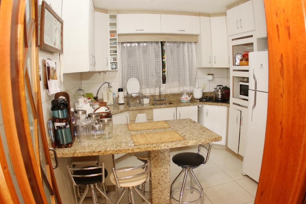 uma cozinha com armários brancos e uma bancada em mármore em SCHUCH - POUSADA em Treze Tílias