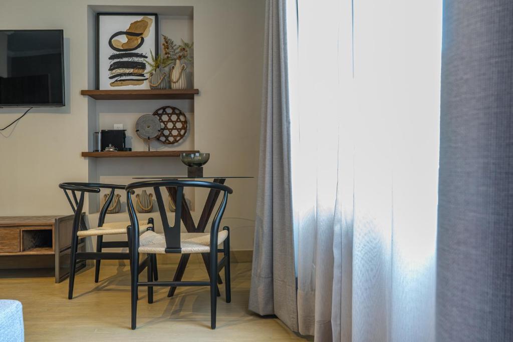 A living-room dining corner with a small round table, four chairs, and a curtained window.