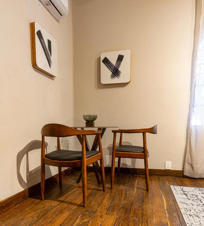 A compact two-chair table set beside a bright curtained window.