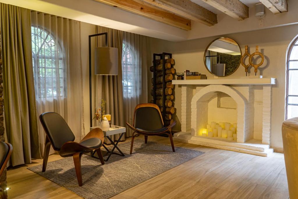 A warmly styled sitting room with a pale stone fireplace, arched windows and lounge chairs.
