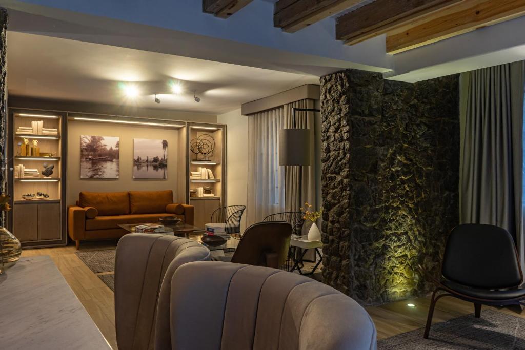 A dimly lit lounge viewed from behind a curved sofa, with stone columns and built-in shelves.