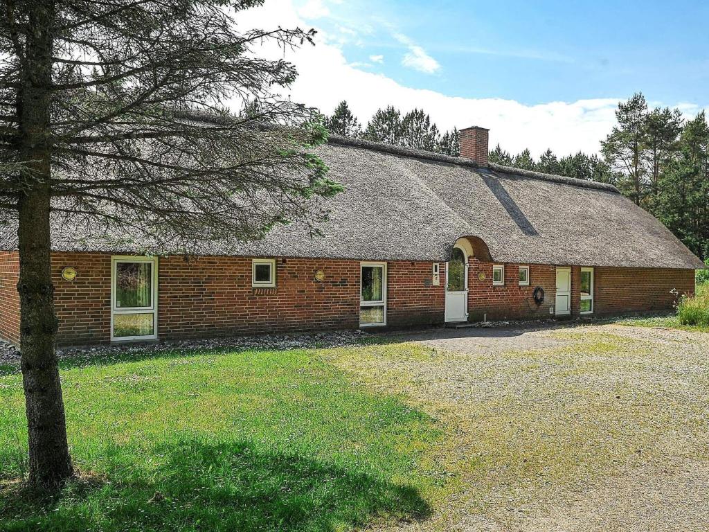 uma casa de tijolos vermelhos com uma árvore em frente em 16 person holiday home in Ulfborg em Ulfborg