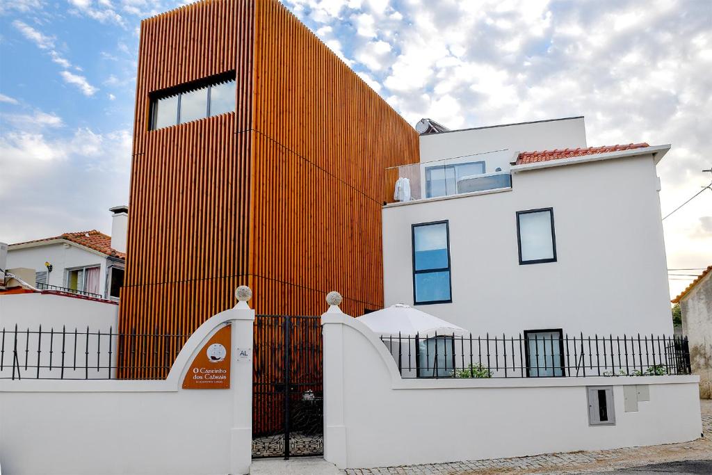 a building with an orange wall behind a fence at O Cantinho dos Cabrais in Inguias