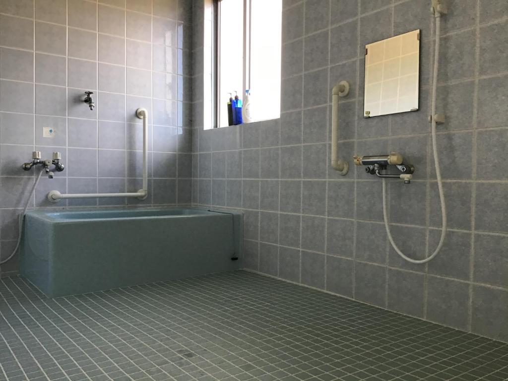 a bathroom with a tub and a shower with a mirror at Shimaotoya in Iriomote