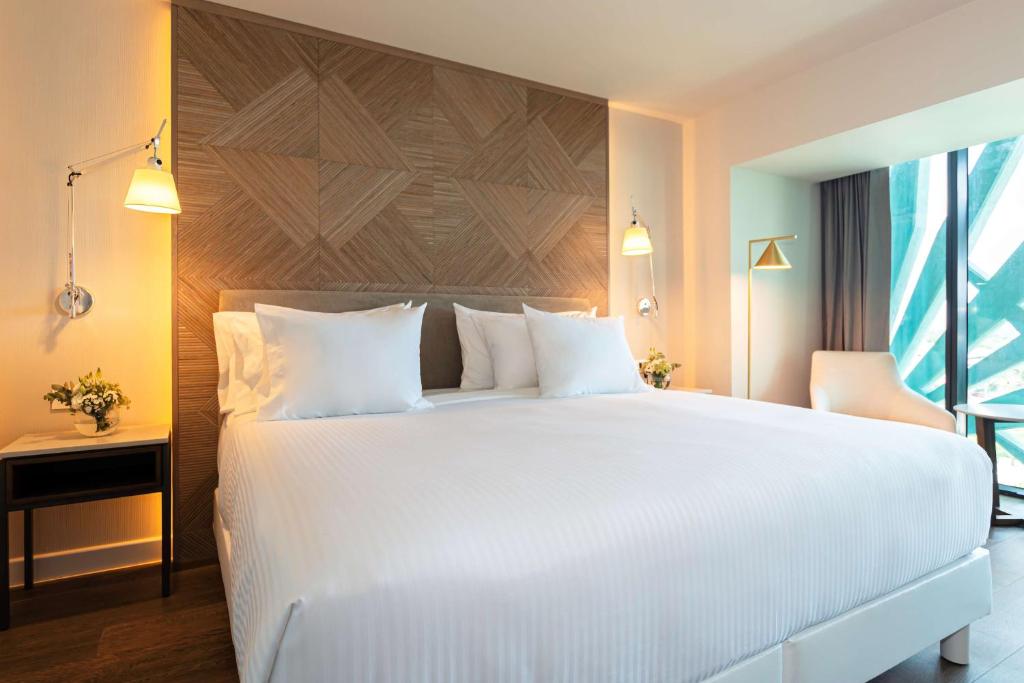 a hotel room with a large bed and a large window at NH Collection Merida Paseo Montejo in Mérida
