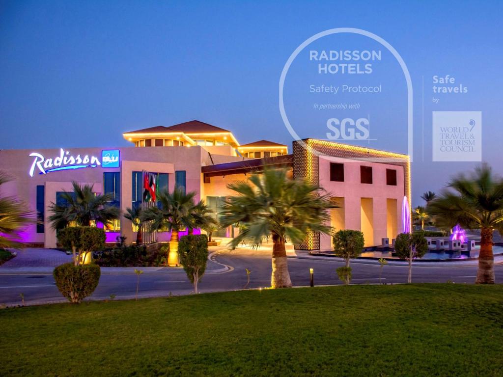 a group of buildings with palm trees in the foreground at Radisson Blu Resort, Al Khobar Half Moon Bay in Half Moon Bay