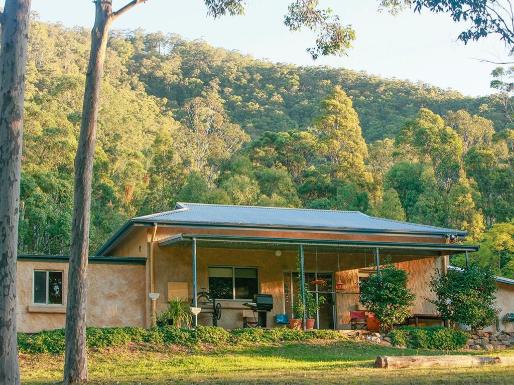 a house with a mountain in the background at Lyrebird Studio in the Watagans in Ellalong