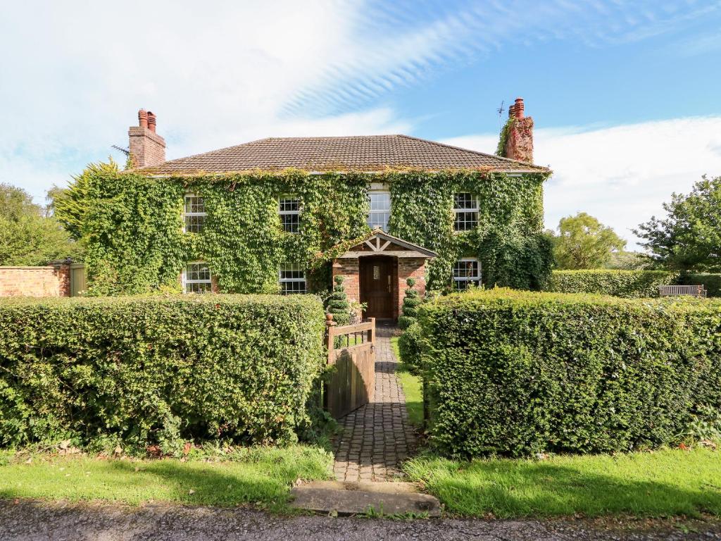 an ivy covered house with a gate and a hedge at The Farmhouse in Skegness