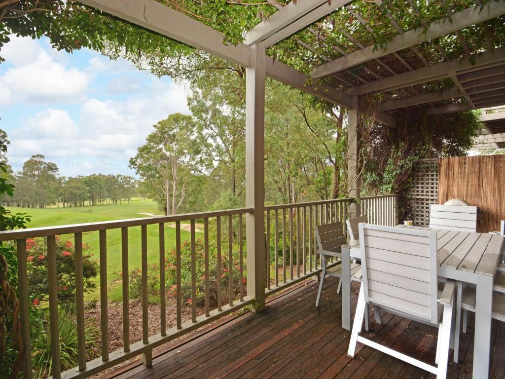 un patio con tavolo e sedie su un ponte di Villa 2br Vermentino Villa located within Cypress Lakes Resort a Pokolbin