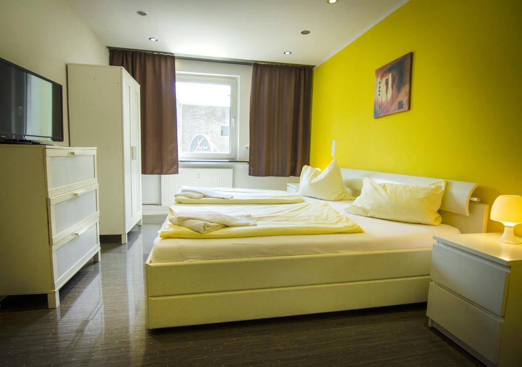 a bedroom with two beds and a yellow wall at Ringeltaube – Wohnen wie zu Hause in Wuppertal