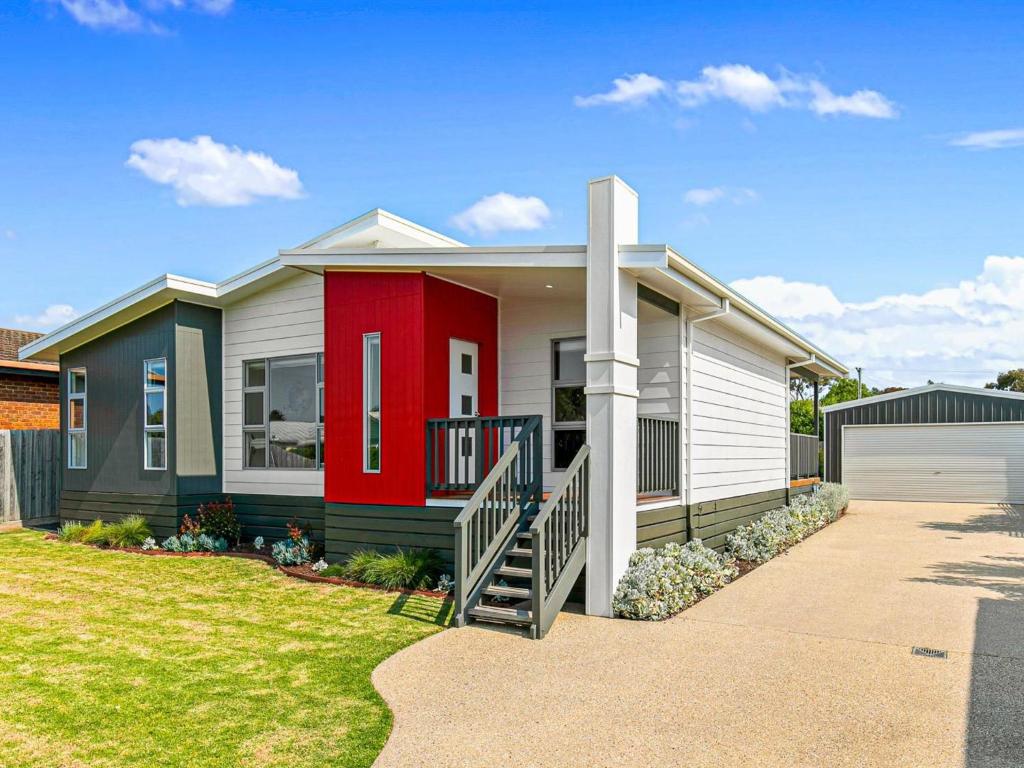 una casa con una puerta roja y un garaje en El Sueno, en Cowes