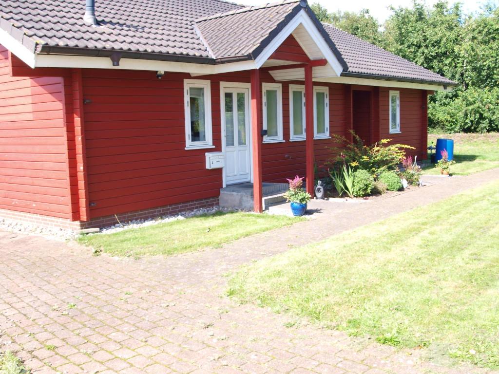 a red house with a brick driveway in front of it at Bjælkehytten in Handewitt