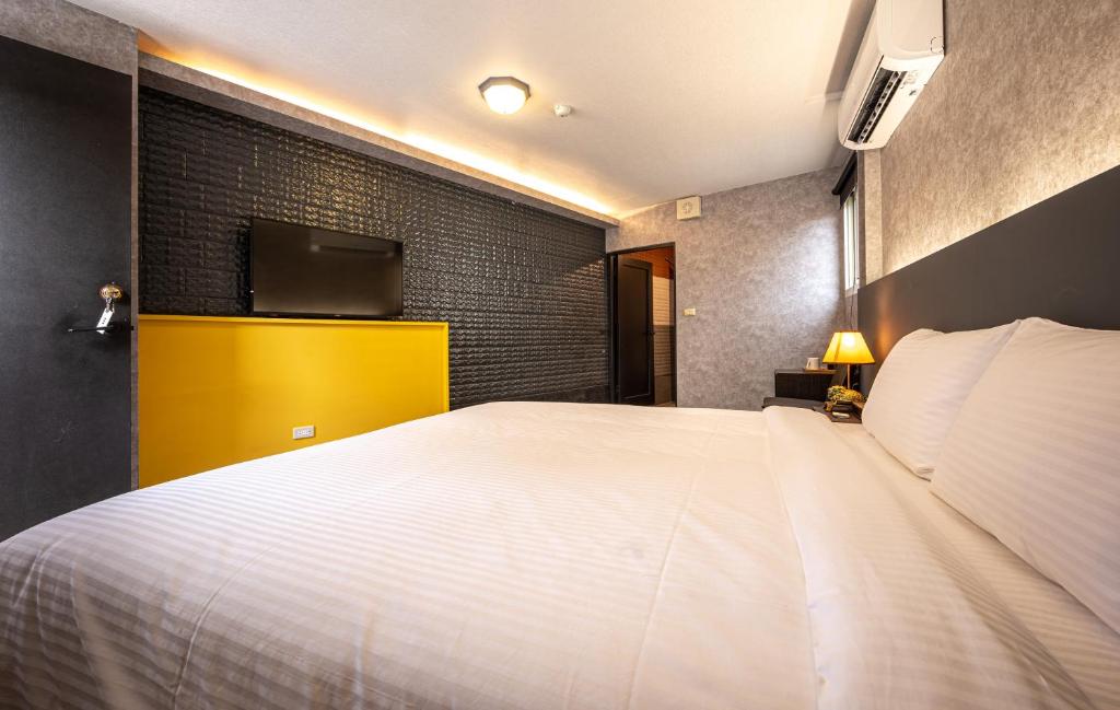 a bedroom with a large white bed and a tv at 東旅驛棧 in Jiaoxi