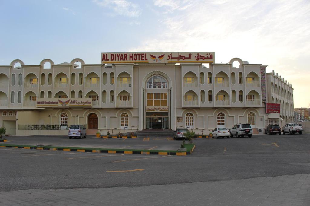 a large building with cars parked in a parking lot at Al Diyar Hotel in Nizwa