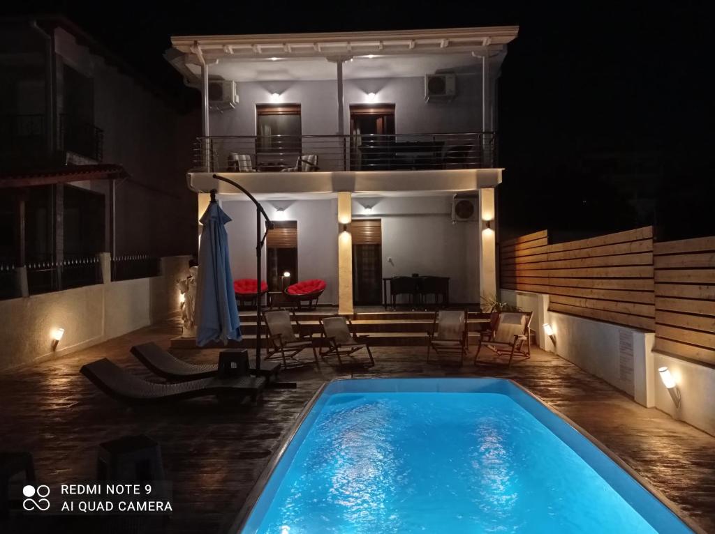 a swimming pool in front of a house at night at Villa Athina 1st floor in Nea Kallikrateia