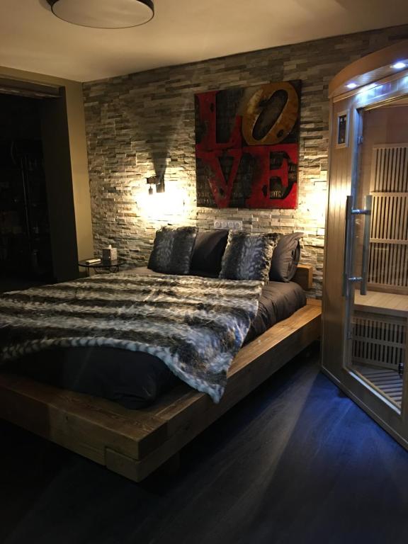 a bedroom with a large bed with a brick wall at Love and Spa in Meynes