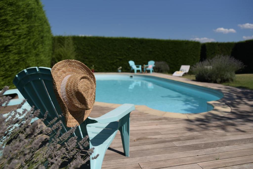 a hat sitting on a bench next to a swimming pool at Les Bessonnes in Saint-Georges-Haute-Ville