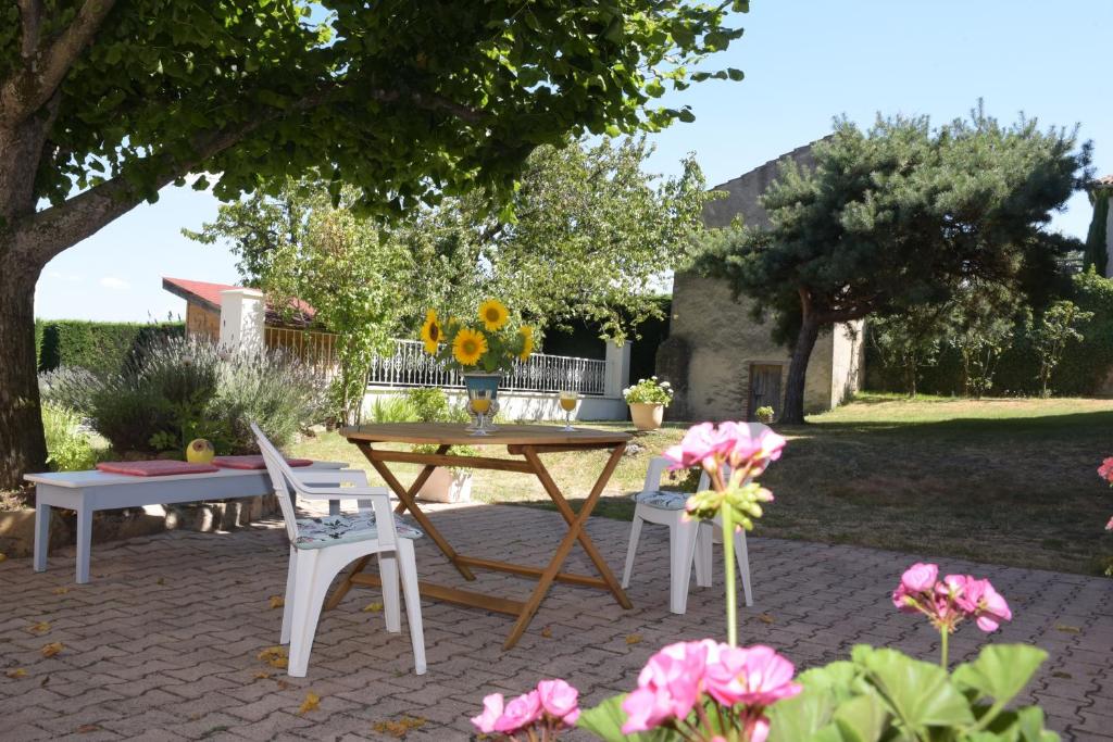 a patio with a table and chairs and flowers at Les Bessonnes in Saint-Georges-Haute-Ville