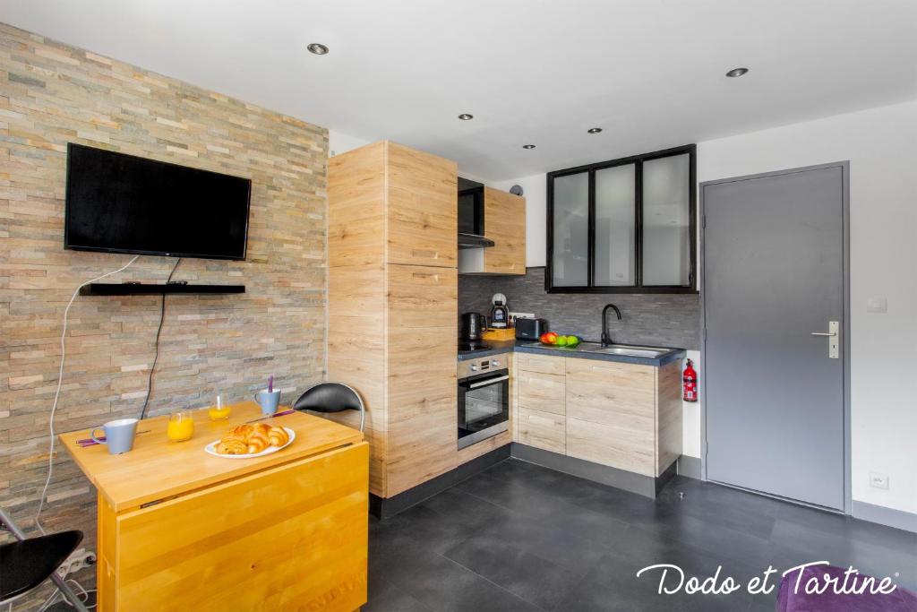 uma cozinha com um balcão de madeira e uma televisão na parede em Lovable studio close to the beach - Dodo et Tartine em Saint-Cyr-sur-Mer